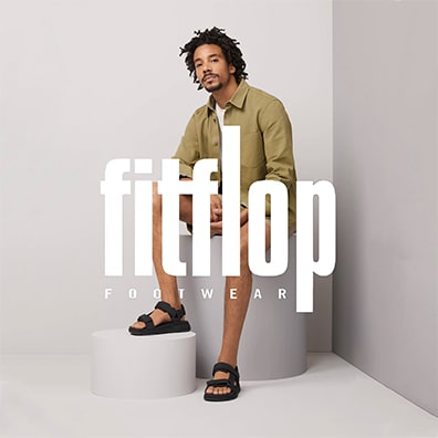 Man sitting wearing fitflop sandals with logo on top