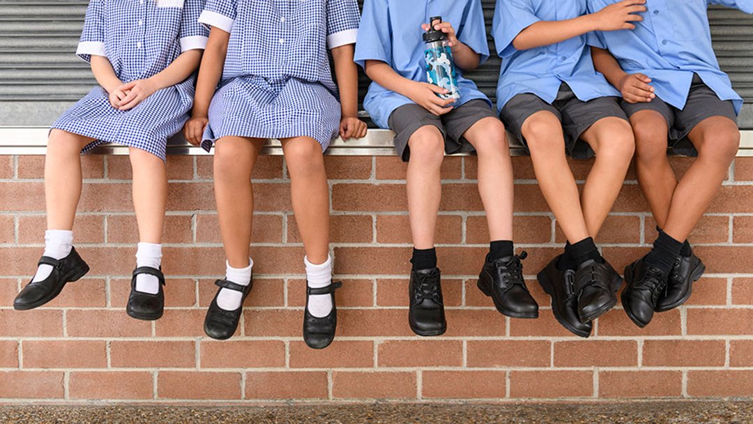 school kids sitting on a wall